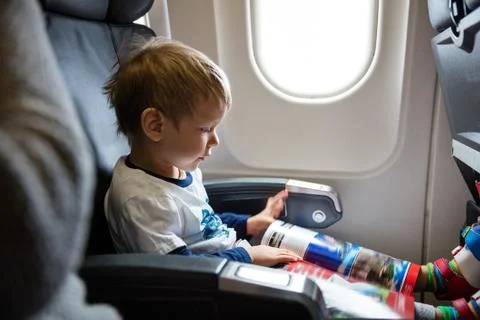 Little boy reading magazine while on board of airplane Stock Photos