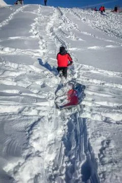 Little Boy in Red Coat Pulling Sled on Snowy Hill Foto stock