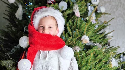 Little boy in red Santa hat dancing near Christmas tree. Joyful mood of child be Stock Footage 167617688