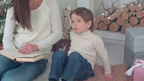 Little boy refusing to read a book together with his mom on Christmas eve 動画素材 70387564