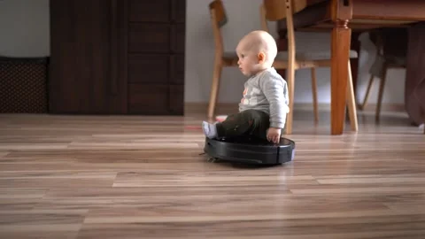 Little boy rides an automatic vacuum cleaner and cleaning room Stock Footage 220631538