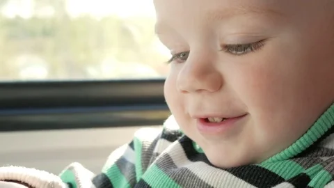 The little boy is riding in a moving train near the window. He smiles and looks Stock Footage 76313731