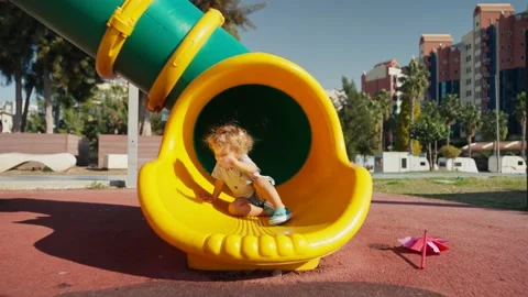 A little boy rolls down a slide on the playground in autumn sunny day Vídeos de archivo 228465952