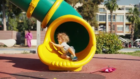 A little boy rolls down a slide on the playground in autumn sunny day Stock Footage 228467697