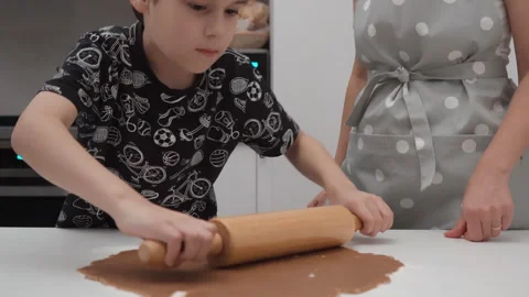Little boy rolls out gingerbread pastry dough with rolling pin in home kitchen Stock Footage 337500715
