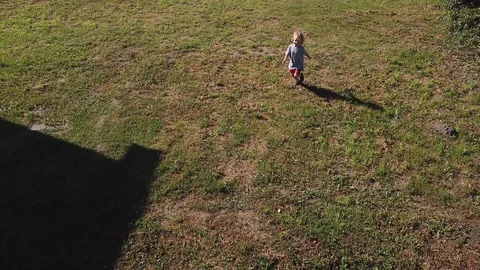 Little boy running in front of camera of drone. Aerial. Stock Footage 94043176