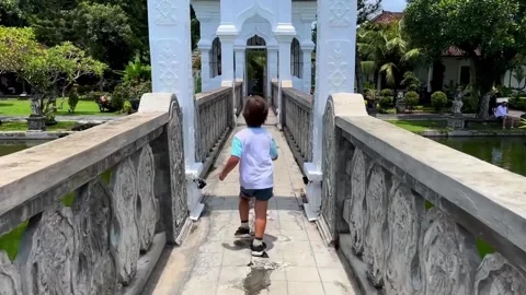 A little boy is running merrily across the beautiful bridge of an ancient Stock Footage 276460434
