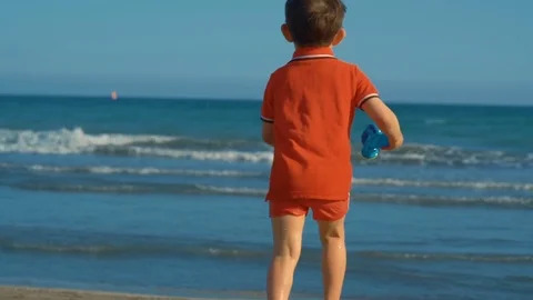 A little boy running on the sandy beach by the water in slow motion Stock Footage 76927074
