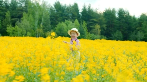 Little boy is running through the field with yellow flowers and smiling Stock Footage 78893515
