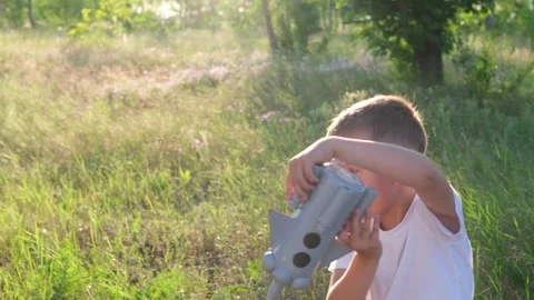 Little boy running with a toy rocket in a sunset field of summer nature. Video stock 246500514