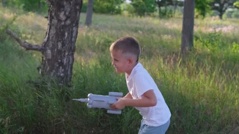 Little boy running with a toy rocket in a sunset field of summer nature. Video stock 246500528