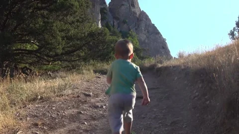 A little boy runs along a path in the mountains Stock Footage 130875989