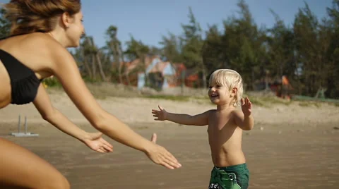 A little boy runs down the beach toward his mother for a big hug. Stock Footage 49671878