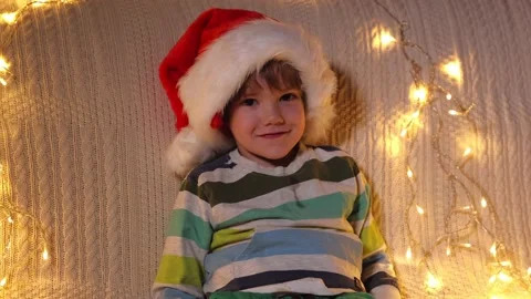 A little boy in a Santa hat is looking at the camera and smiling at holiday Stock Footage 164992913