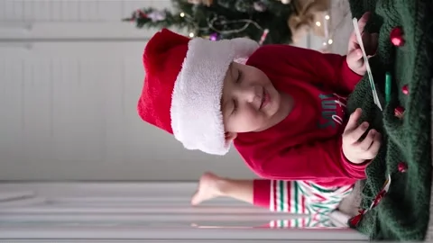 A little boy in a Santa hat waves his hand while looking at the camera. Stock Footage 257525004