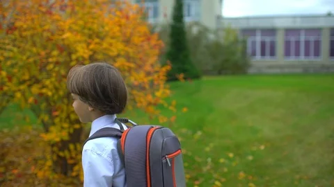 Little boy schoolboy student with backpack going to school outdoors, First-grade Stock Footage 100102930