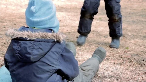 Little boy sit on ground and watch his friend playing with branch Stock Footage 76561998