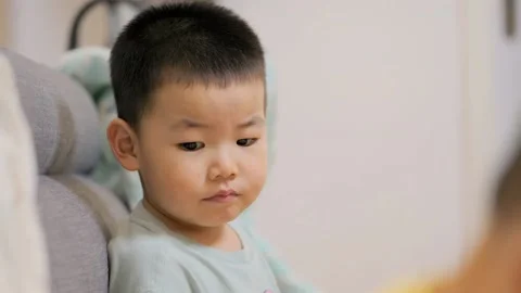 A little boy sits in a daze on the sofa in the living room at home Stock Footage 156228002