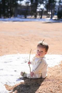 Little boy sits on snowy patch Stock Photos