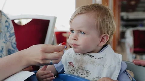 A little boy sits at the table and his mother feeds him berries from her hand Stock Footage 154367716