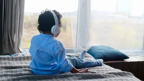 Little Boy Sitting on Bed and Listening to Music on Smartphone Видео 101042291