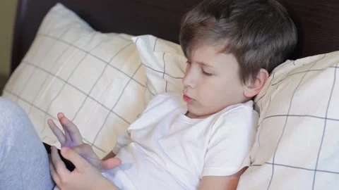 Little boy sitting in bed and using smart phone Stock Footage 159830731