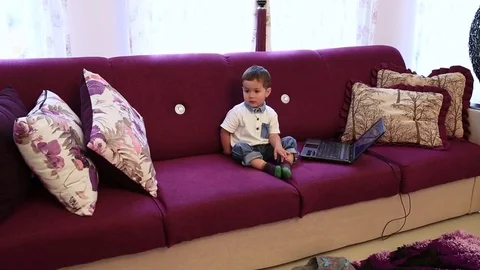 A little boy is sitting on the couch and watching TV Stock Footage 73659867