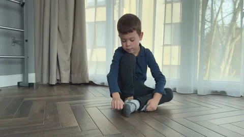 Little boy sitting on floor taking off wool socks in living room and getting Stock Footage 344882060