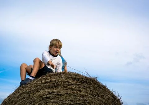 Little boy sitting on haystack in the sky Stock Photos