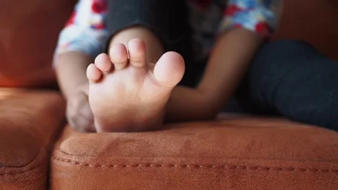 Little boy sitting on sofa and scratching his foot due to fungal infection .. Stock Footage 332745790