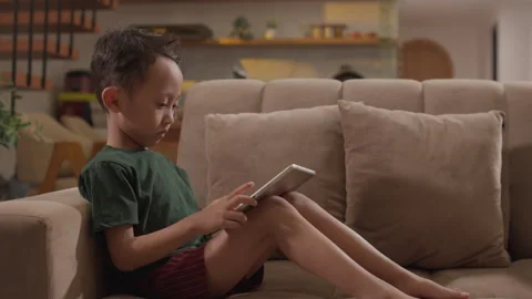 Little boy sitting on a sofa using a tablet Stock Footage 339868339