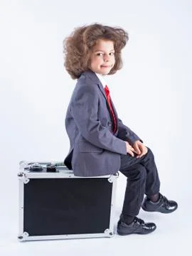 Little boy sitting on suitcase, preparing for the holiday. Business boy, chee Stock Photos