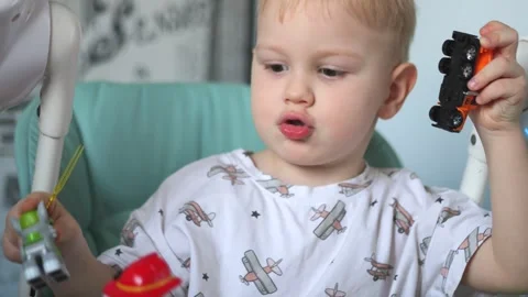A little boy is sitting at a table and eating fruits: a banana and a pear Stock Footage 267539309