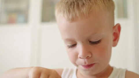 Little boy sitting at a table and eating hot porridge for breakfast at home.  Video stock 335686848