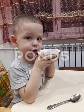 The little boy is sitting at the table and frowning Stock Photos