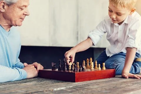 Little boy sitting on the table while playing chess Foto stock