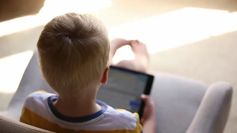 Little boy sitting with tablet or electronic device Vídeos de archivo 137432024