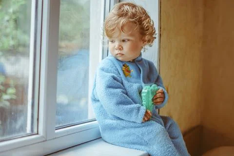 A little boy is sitting by the window Photos