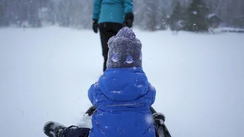 Little boy on a sledge - with mother pulling the rope in the background Stock Footage 104900057