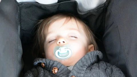 A little boy is sleep in a stroller. Close up portrait of a boy. Selective focus 動画素材 102203878