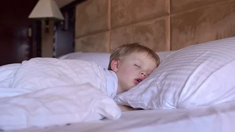 The little boy is sleeping in the bed. Stock Footage