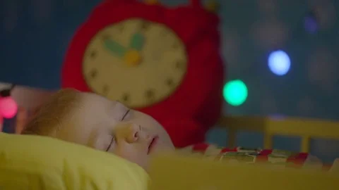 Little boy is sleeping in his cot on Christmas night. Mom is covering him with Stock Footage 73942227