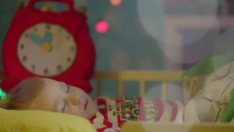 Little boy is sleeping in his cot on Christmas night. Dad is covering him with Video stock 73943560