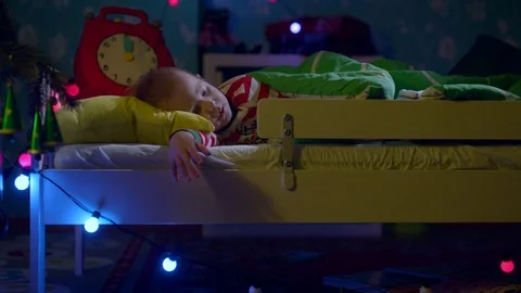Little boy is sleeping in his cot on Christmas night. Mom is bringing him Stock Footage 73944030