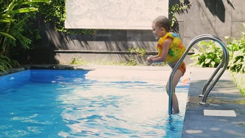 Little boy in sleeves and cap is swimming in the pool on vacation. boy swims in Stockbeeldmateriaal 128490880