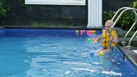 Little boy in sleeves and cap is swimming in the pool on vacation. boy swims in 库存影片 130046155