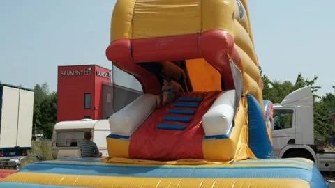 A little boy slides down the slide on the inflatable trampoline in trampoline Stock Footage 240470652