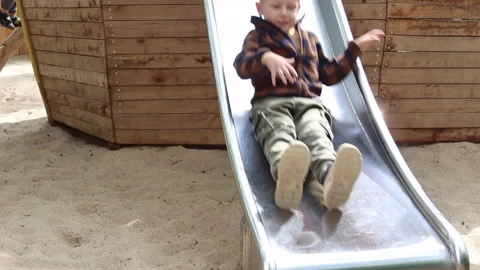 Little boy slides down the slide at the playground	 Video stock 311920769