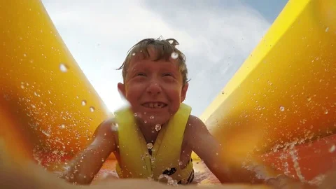 Little boy slides fast by the inflatable slide into the water pool Stock-Footage 71599145