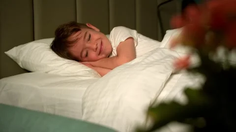 Little boy smiling while sleeping in bed. Cute boy 7 years old at home in his Stock Footage 313751693
